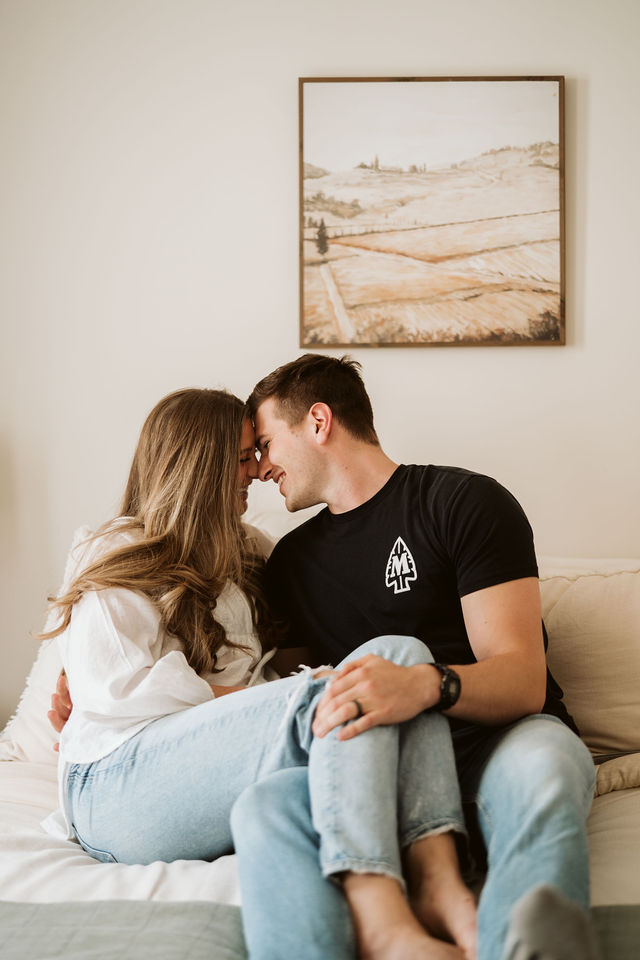 Couple sharing a kiss in a softly lit bedroom.