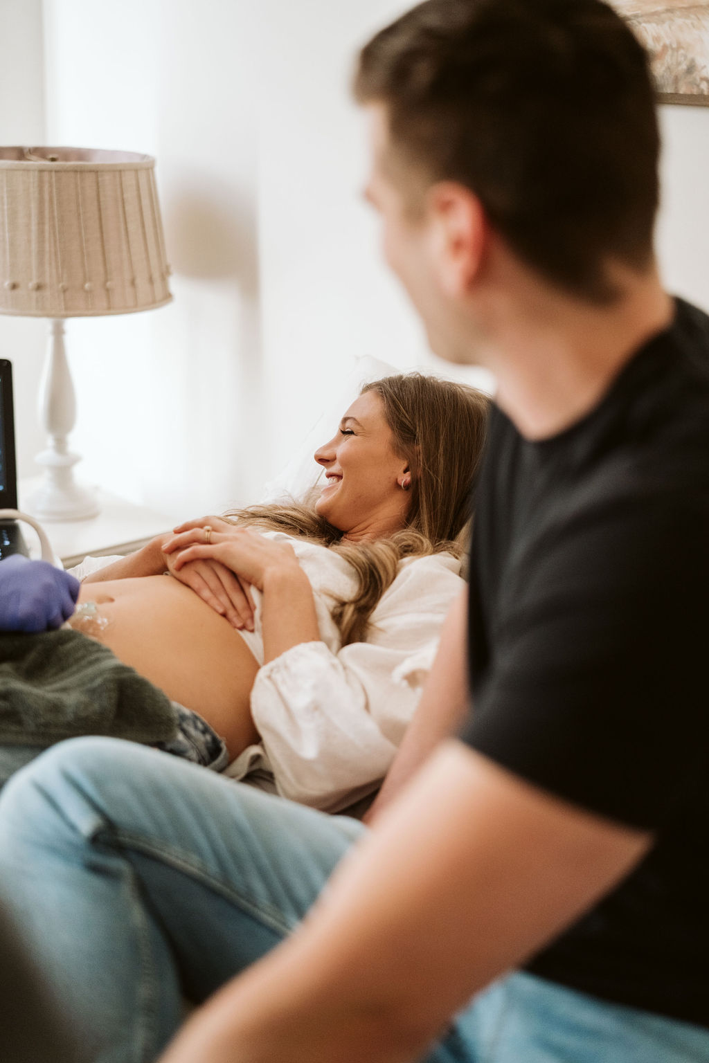Expectant mother smiling with her partner beside her during an in-home appointment.
