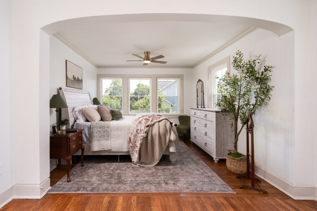 Light-filled bedroom with soft neutral bedding, white furnishings and wood floors