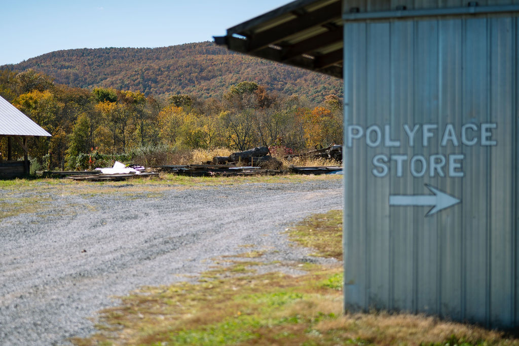 Polyface Store direction sign on a farm building with autumn hills beyond.
