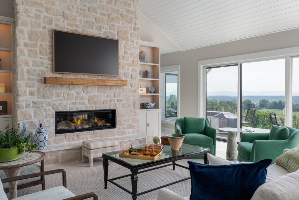 Living room with stone fireplace, green armchairs and broad windows