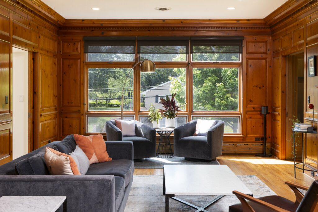 Wood-paneled sitting room with upholstered seating and garden-facing windows